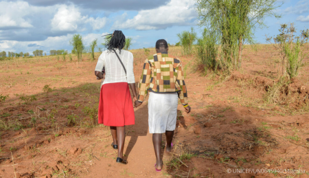 A social worker walks with a young girl in Uganda